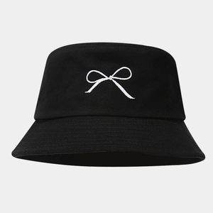 Detailed close-up of a black bucket hat featuring a white bow embroidery on high quality fabric