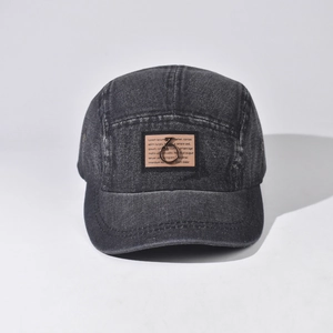 Detail of black washed denim camp cap with vintage patch and metal Z-ring ornament