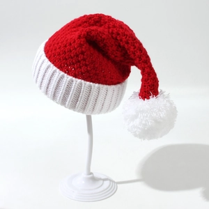Detailed close-up of festive red and white knit Christmas hat with white pom-pom detail