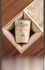 Detail of Ru kiln ceramic tea cup with strawberry rabbit motif in a satin gift box