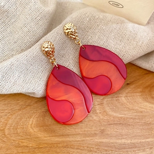 Detailed close-up of water drop earrings with orange marble resin and gold metal texture