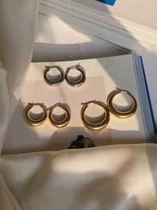 Detailed view of assorted gold and silver polished hoop earrings on white book pages