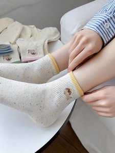 Detail of light beige dotted socks featuring cute dachshund dog embroidery and yellow trim