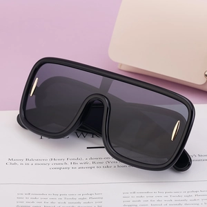 Detail shot of black oversized sunglasses with gold metal trim on a fashion magazine