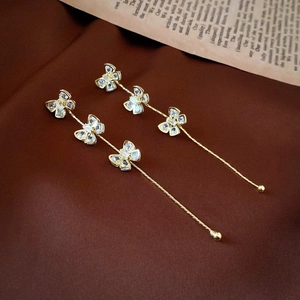 Detail of long gold bow tassel earrings featuring sparkling zircon crystals and delicate chains