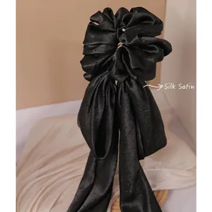 Elegant black satin hair scrunchie with long ribbons and a stylish bow design