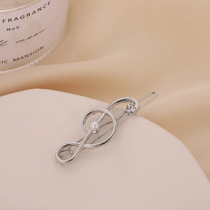 Close-up of silver musical note hair clip with white pearl and sparkling rhinestone