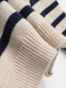 Detail of ribbed cuffs on a beige and navy striped knit sweater with soft fuzzy texture