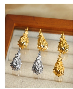 Macro-detail van druppelvormige oorbellen met getextureerde goud en zilver op beige fluweel