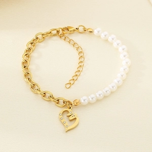 Detail of gold heart pendant pearl and titanium steel link bracelet on beige background
