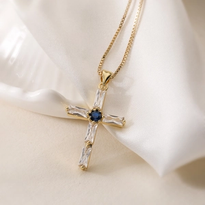 18K gold plated cross pendant necklace with clear zircon and blue gemstone on white silk