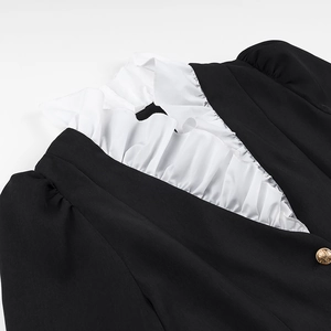 Detail of black dress collar with white ruffle trim and a single gold button accent
