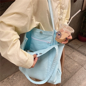 Detail of light blue canvas tote bag showing magnetic closure and internal zipper pocket