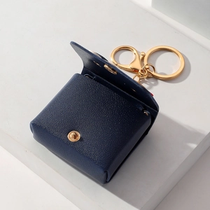 Dark blue leather flower coin purse keychain with gold buckle on white geometry