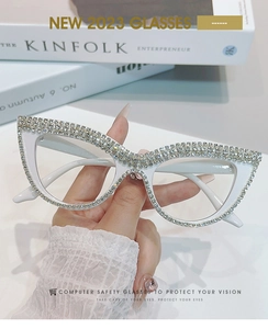 Dettaglio degli occhiali cat-eye bianchi con strass incastonati e lenti trasparenti