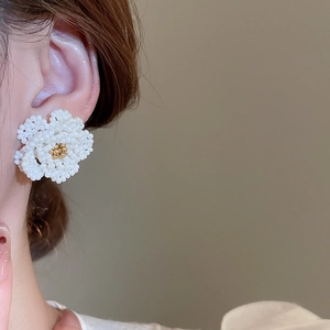 Close-up of model wearing camellia pearl beaded earrings in white and gold