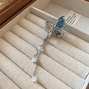 Détail de la pince papillon avec ailes en résine bleue et longues chaînes à pompons