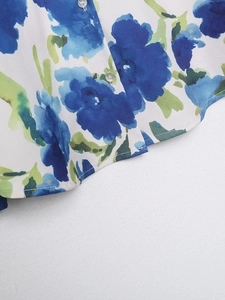 Détails d'une chemise en satin avec imprimé floral, coutures précises et boutons soignés