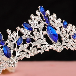 Detailed close-up of a royal silver tiara featuring blue crystals and intricate rhinestones