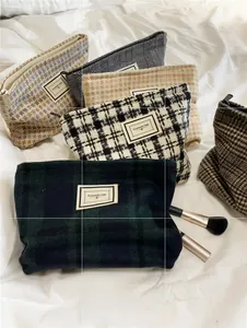 Macro shot of assorted tweed plaid cosmetic bags with retro woven labels on white fabric