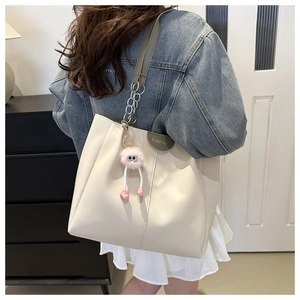 Dettaglio della borsa tote beige in pelle PU con finiture verdi e ciondolo in peluche rosa