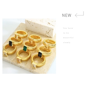 Detail of colorful rectangular gemstones set on matte gold ripple-textured rings
