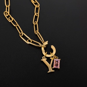 Makro-Detail der 14K vergoldeten Halskette mit Initial-Y und rosa Kristallanhänger.
