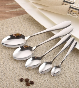 Lot de cinq cuillères en acier inoxydable poli de tailles variées sur une serviette beige