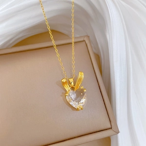 Detail shot of heart shaped crystal necklace with rabbit ear design in gold finish