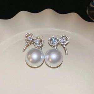Détail macro de boucles d'oreilles nœud en strass avec perles sur plateau céramique