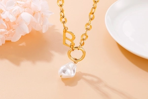 Detail of gold B letter pendant necklace with baroque pearl on thick chain link