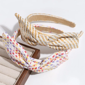 Detail of woven bow headbands in beige and multicolor on a wooden display tray