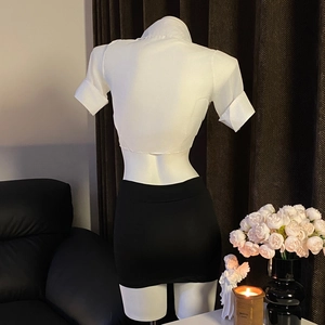 Vue arrière du haut court blanc sexy et de la mini-jupe noire moulante en ensemble uniforme