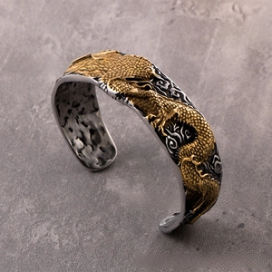 Macro detail of retro dragon relief and cloud texture on vintage stainless steel cuff