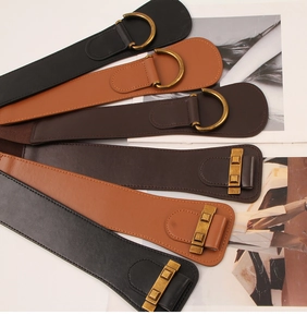 Detail view of six vintage elastic wide waist belts in black and brown with metal buckles