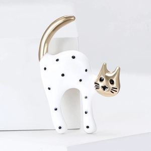 Close-up of cute enamel cat brooch with black polka dots and gold-plated alloy finish