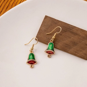 Detail shot of Christmas bell earrings with red and green enamel on a wooden block
