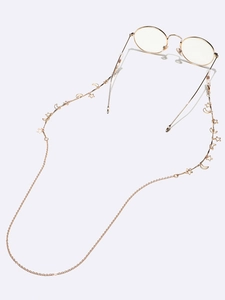 Detailaufnahme der goldenen Brillenkette aus Metall mit Sternen, Mondanhängern und Schlaufen