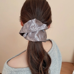 Back view of a model wearing a large silver satin scrunchie on a ponytail