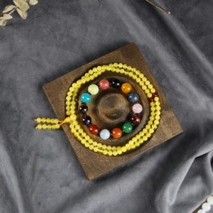 Macro detail of wooden display tray holding colorful beaded bracelets and necklaces