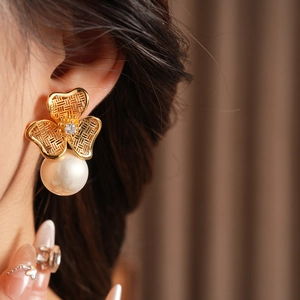 Detail of vintage flower earrings with pearl drop and zircon stone shown on model