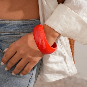 Detail view of chunky red acrylic geometric bangle styled with a white shirt and denim