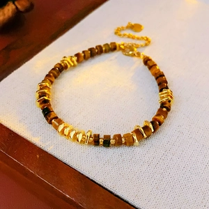 Macro detail of tiger eye stone beads and golden spacers on a metal bracelet charm
