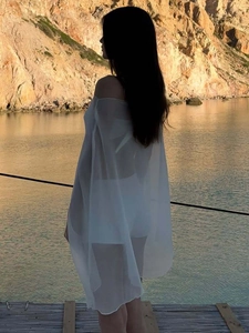 Casual white sheer chiffon beach cover up blouse for women in an outdoor seaside setting