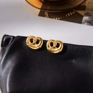 18K gold plated stainless steel pretzel heart earrings on black leather texture