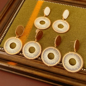 Detailed view of handmade woven hoop earrings with metallic spokes in three earthy colors