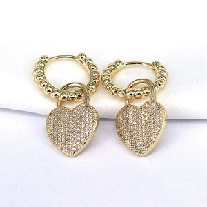 Macro shot of gold heart earrings with white cubic zirconia and beaded hoop detail