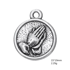 Macro detail of antique silver praying hands medal charm with 15x19mm dimensions