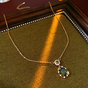 Detail of gold butterfly pendant featuring green emerald stones and zircon accents