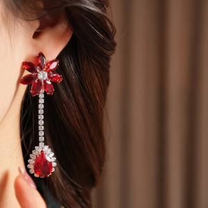 Close-up of elegant silver drop earrings with vintage red flower and zircon crystals